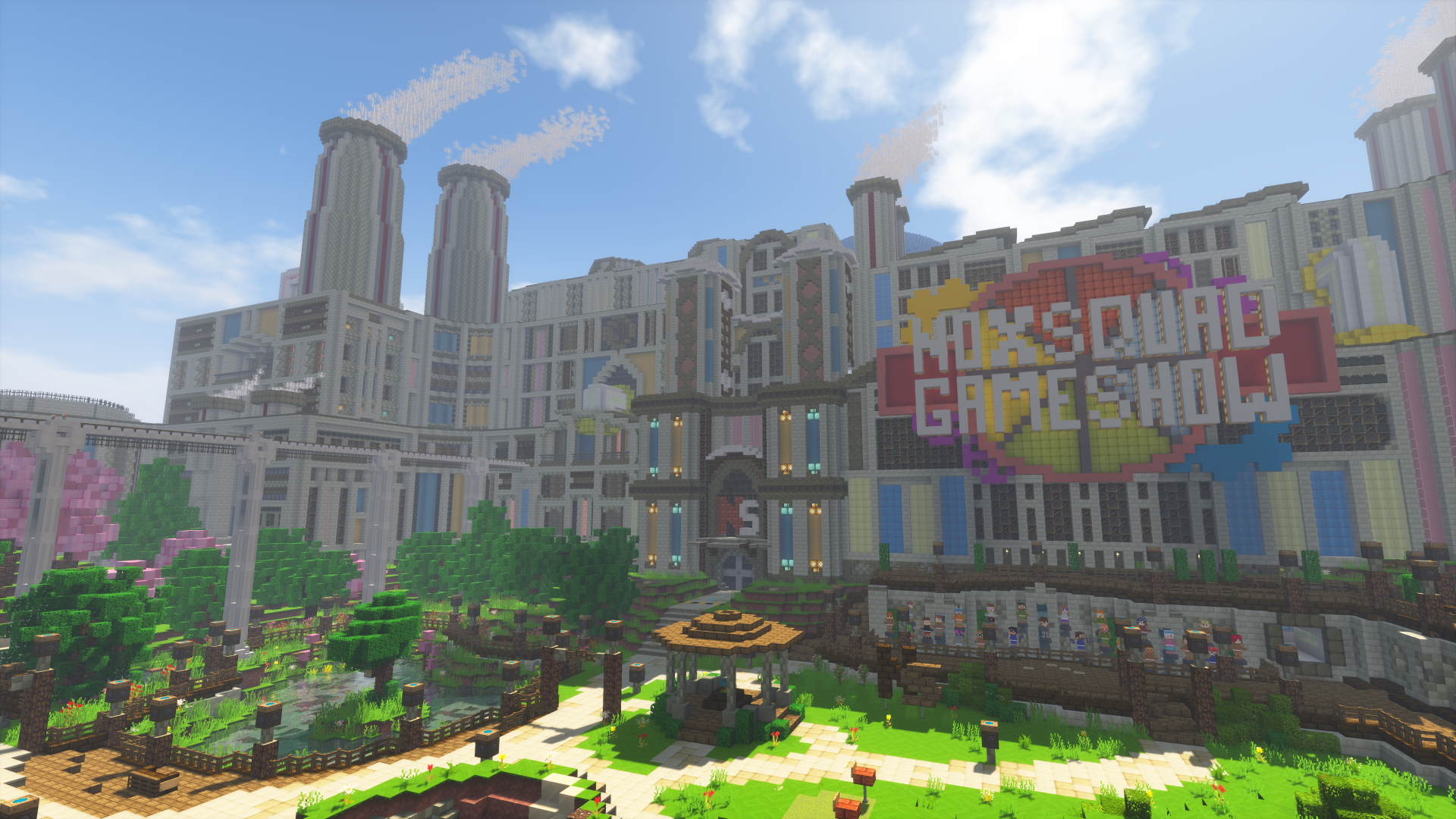 A screenshot within Minecraft of the Noxsquad Gameshow Factory. The logo of the Noxsquad Gameshow is shown many metres tall on the wall of the factory. In front of the factory are gardens, a bandstand, a decking area with statues, and a pond with a tree in the middle of it. The walls of the factory have large pipes coming out of them in various places, and the walls themselves are composed of different panels, many of which are blue and yellow. There are large chimneys on the roof with smoke coming out of them, and the glass roof of the Decision Dome can be seen slightly in the background.